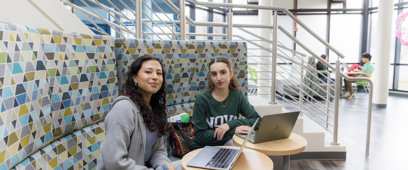 students sitting together on a table with laptops out.